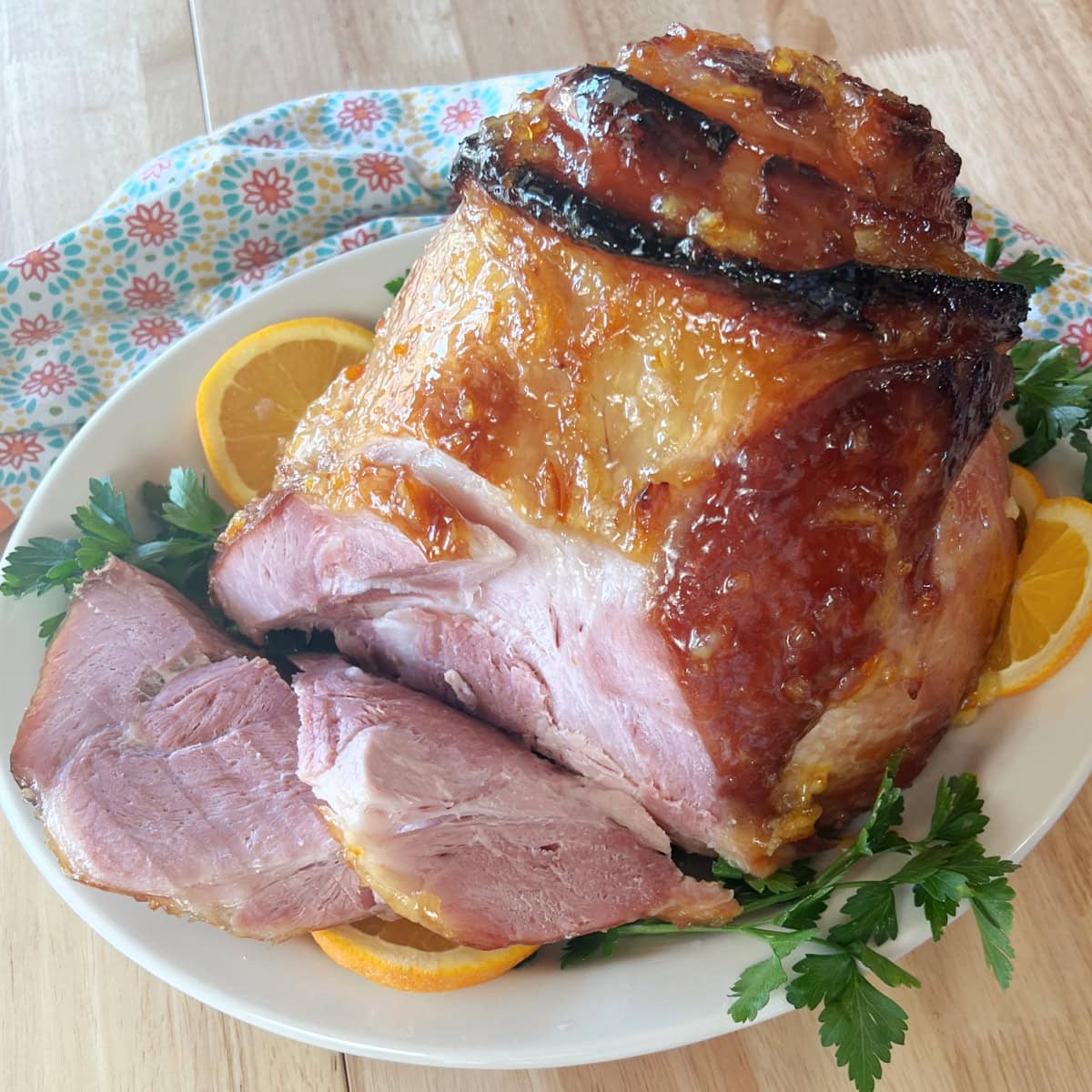 Easy maple glazed half of ham plated with garnish and oranges.