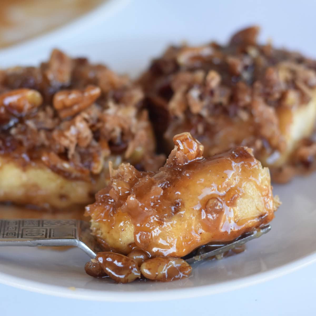 A bite of caramel pecan rolls made from pillsbury cinnamon rolls.