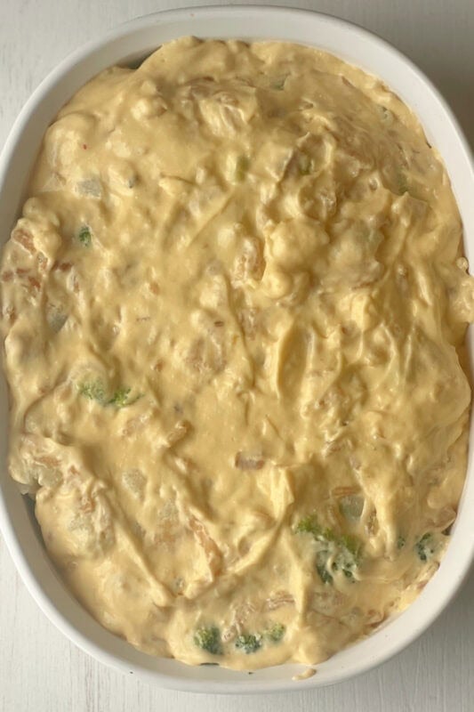 Cheese sauce spread out evenly over the broccoli and cauliflower florets in the casserole dish .