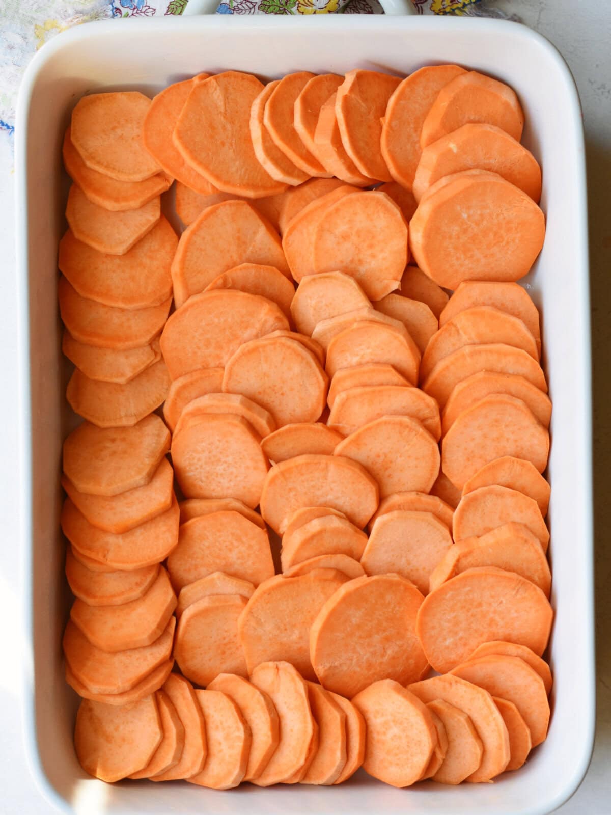 scalloped-sweet-potatoes-layer Sliced potatoes on layered on the bottom of a baking dish.