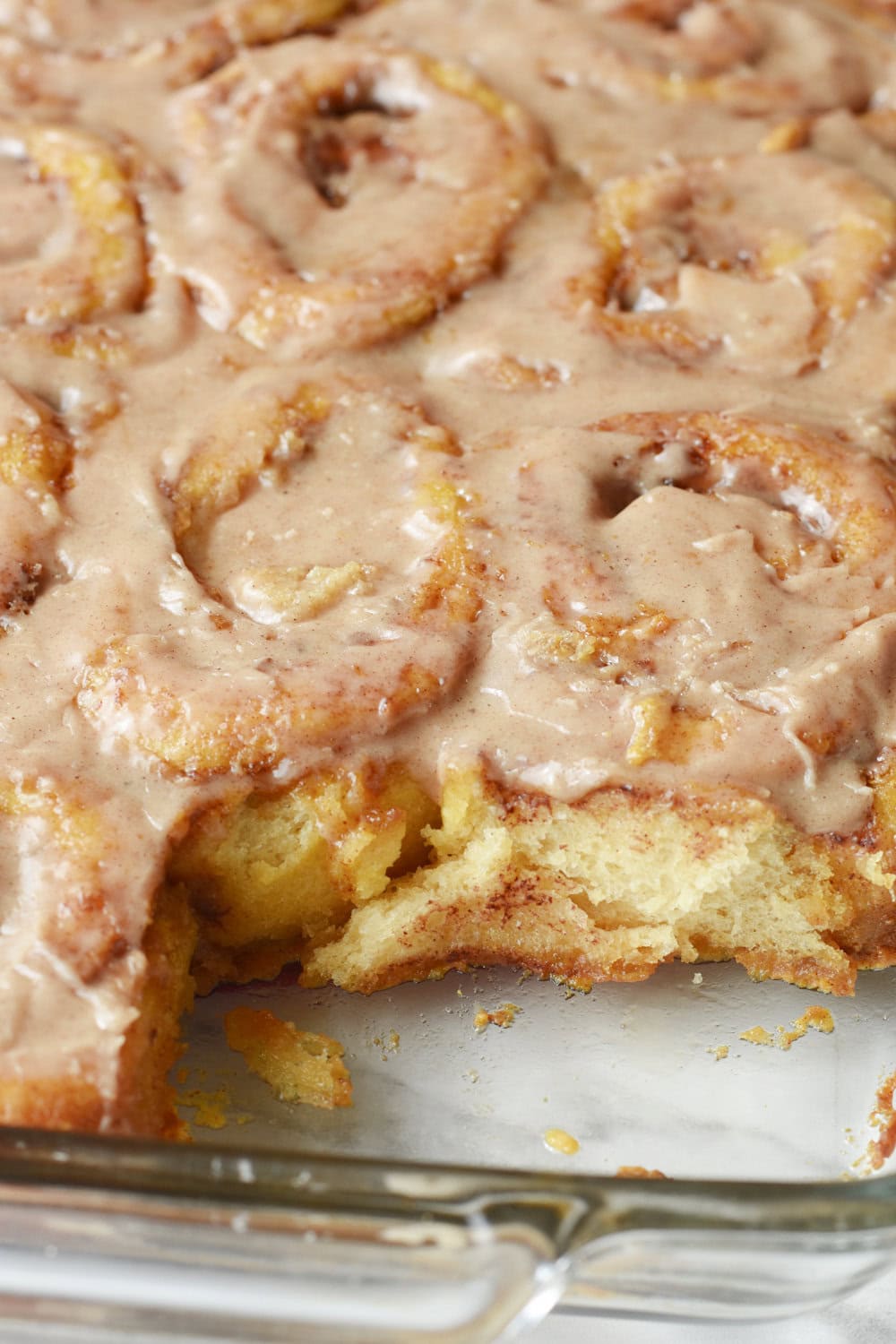 Frosted Pumpkin Cinnamon Rolls ready to be served with one cinnamon roll pulled out. 