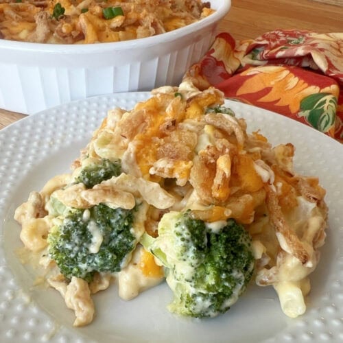 A serving of broccoli cauliflower cheese casserole on a white plate.