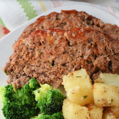 A slice of meatloaf with broccoli and cubed potatoes.