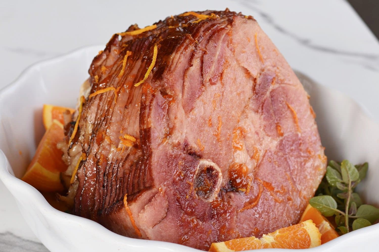 Spiral ham made in an instant pot on a serving platter with oranges and garnish.
