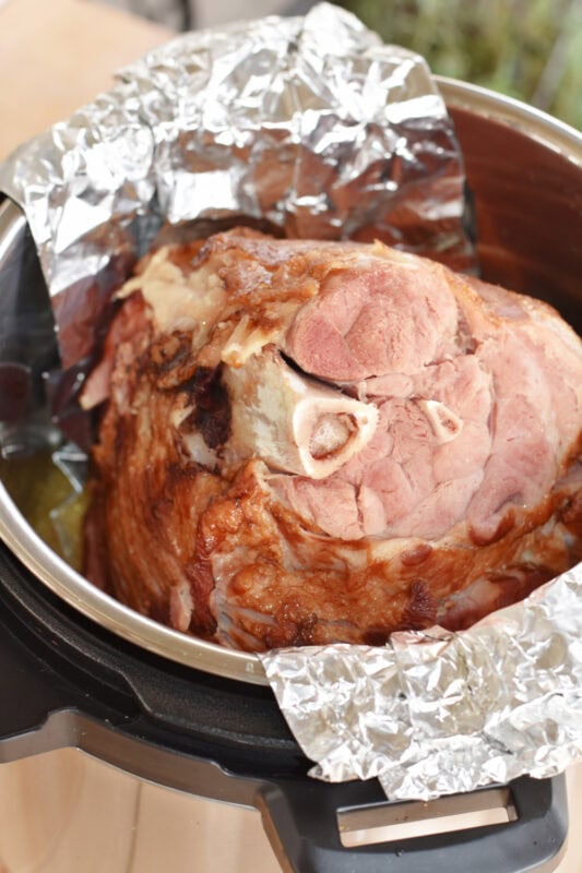 Ham in a foil sling in a pressure cooker with orange juice.