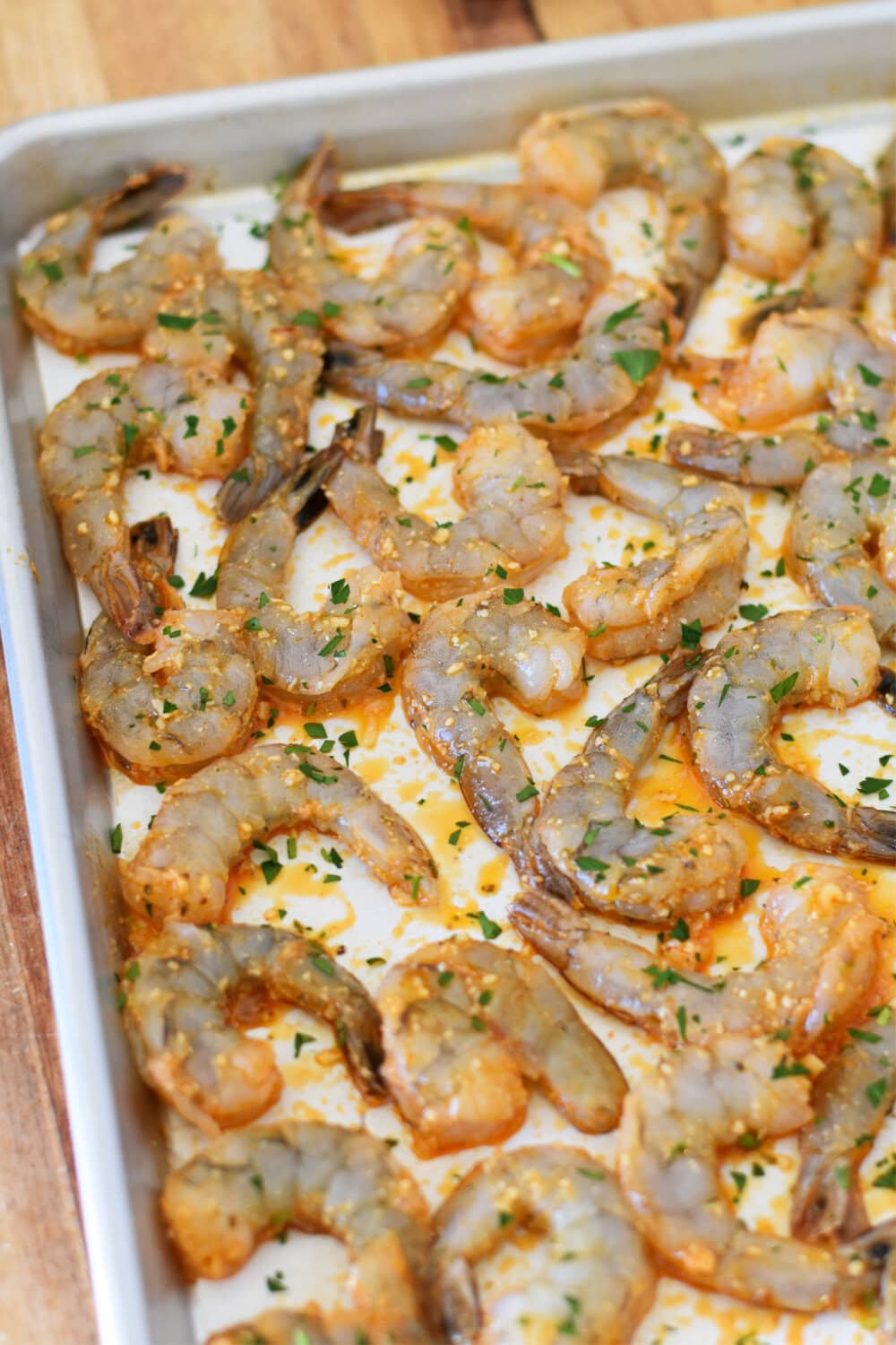 Raw shrimp spread out for cooking in the oven. 