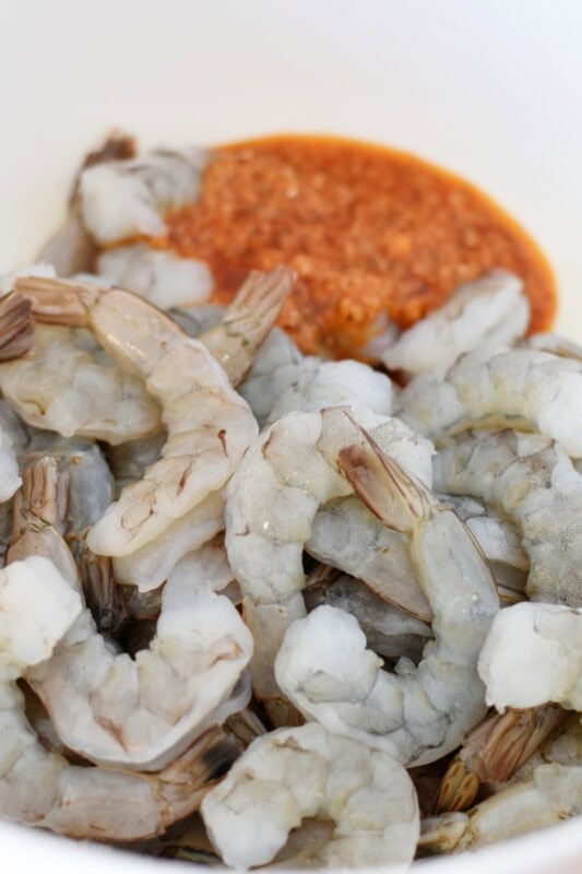 Shrimp in a mixing bowl with sauce. 