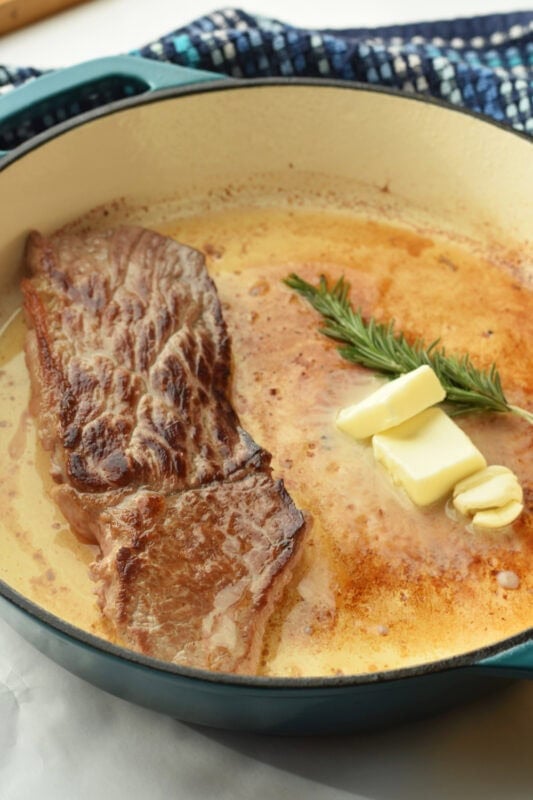 round-steak-searing Searing beef in a cast iron skillet with butter and garlic.