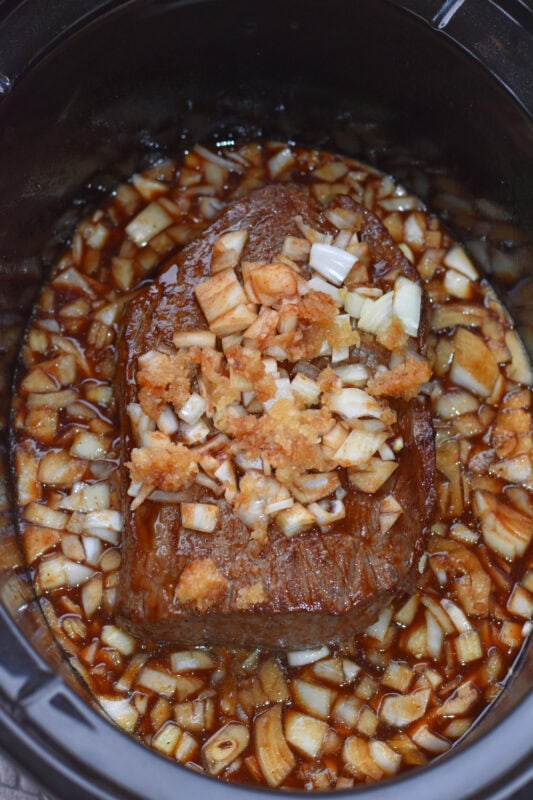 Balsamic vinegar, beef, beef broth, onions and garlic with seasonings in a crock pot.