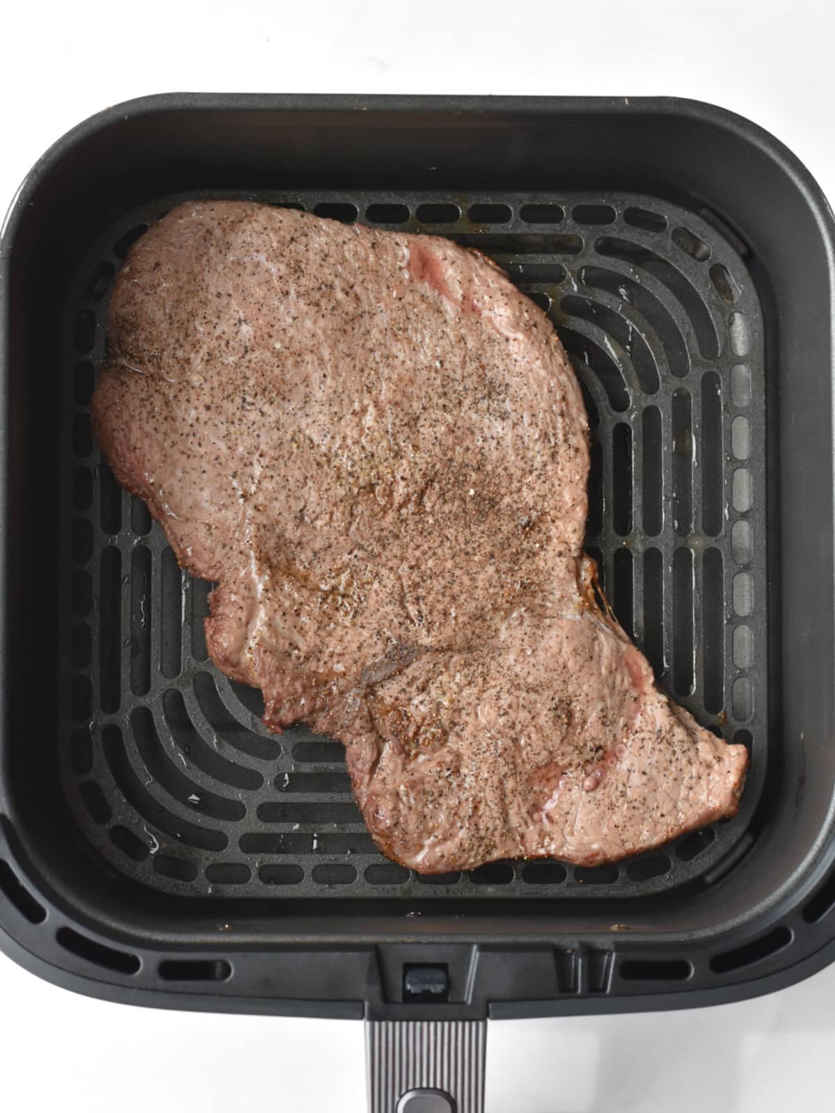 Partially air fried beef in the air fryer basket. 