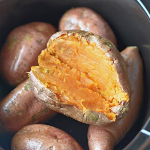 A potato cut open stacked in a slow cooker.