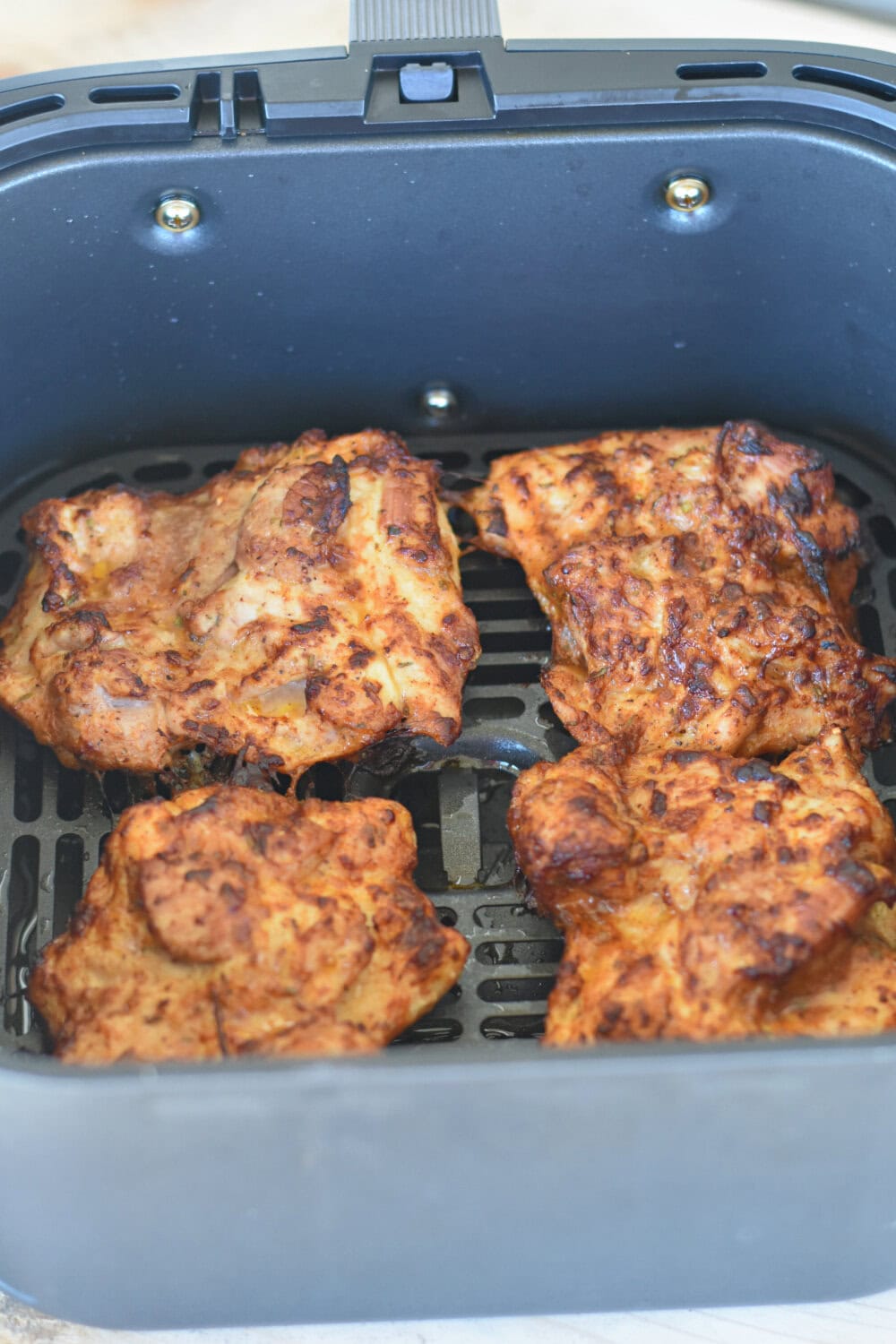 skinless-thighs-air-fryer Boneless, skinless chicken thighs in an air fryer basket.