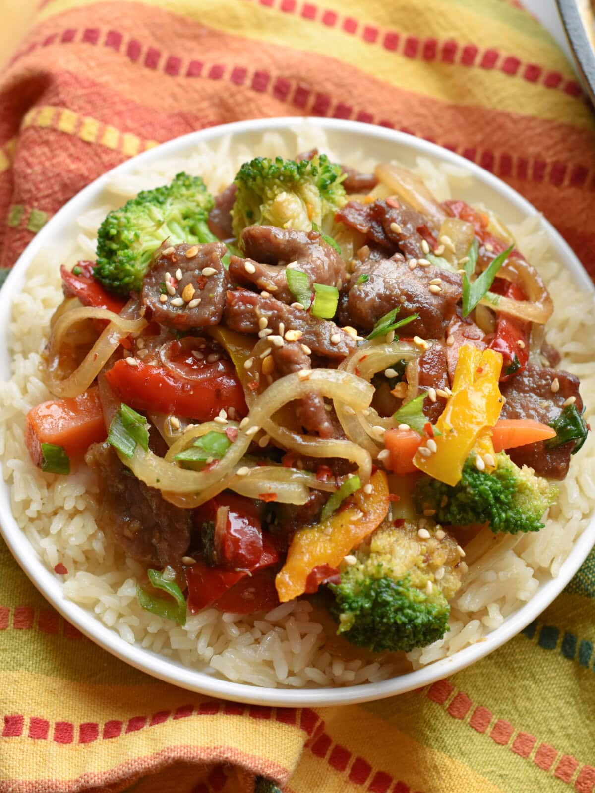 Beef bottom round steak stir fry with broccoli over a bed of rice in a bowl. 