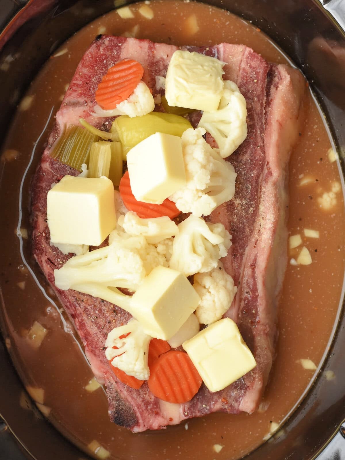 Chuck roast in a slow cooker with a brine and pickled vegetables. 