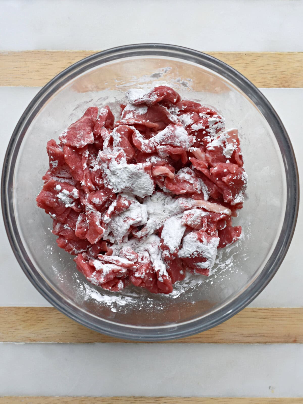Thin sliced steak with flour in a bowl. 