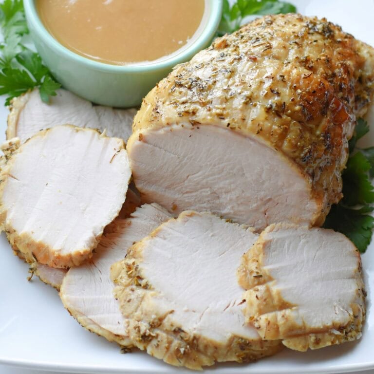 Boneless turkey breast made in the electric roaster oven on a white plate with gravy.