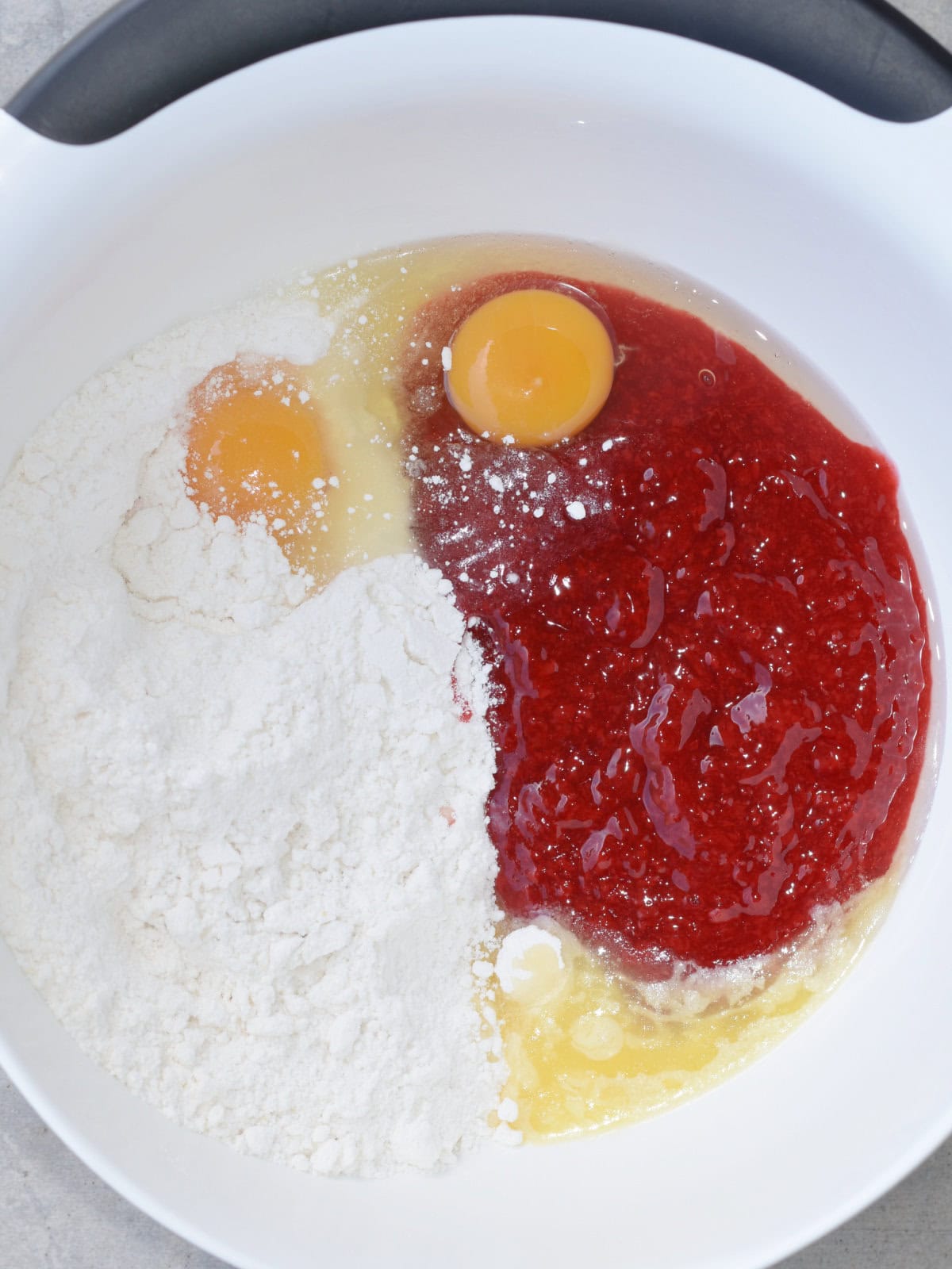 Box white cake mix, cherry pie filling, and eggs in a mixing bowl. 