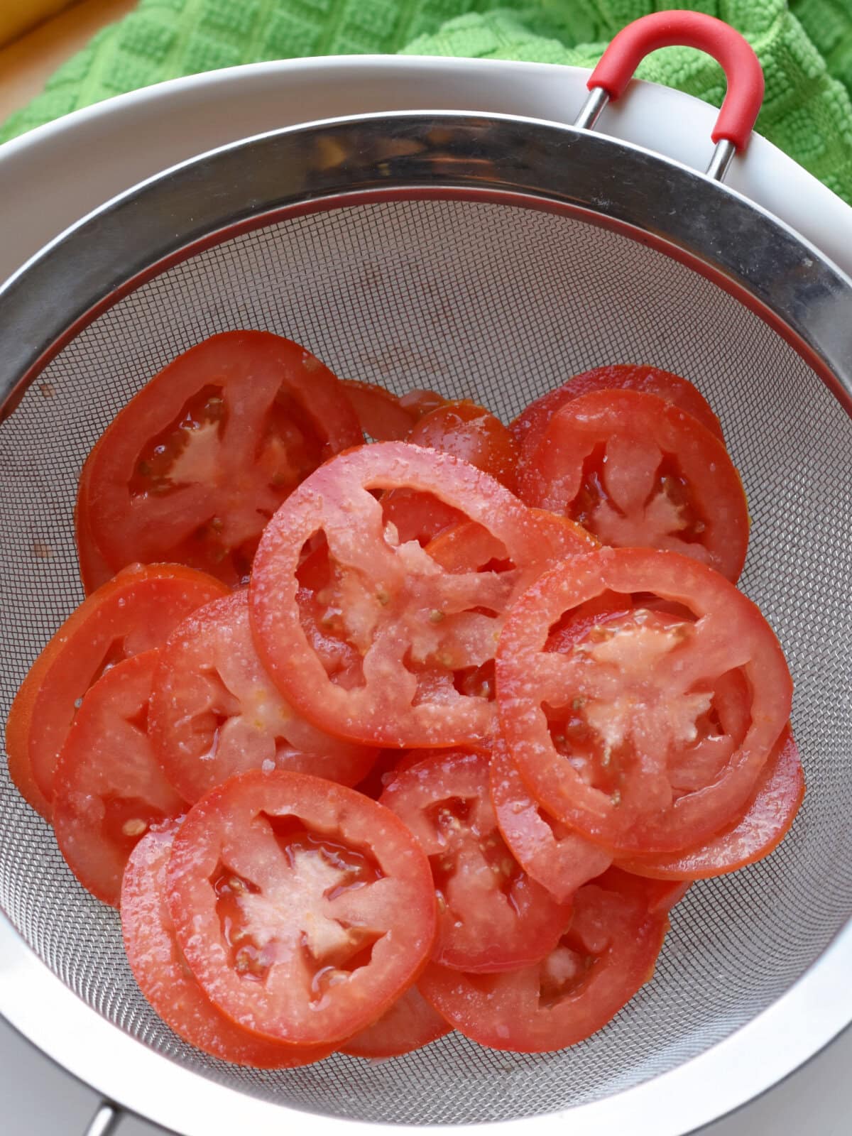 Sliced roma tomatoes in a strainer. 