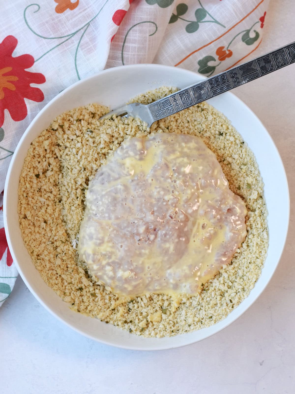 Dredged meat being breaded with panko bread crumbs. 