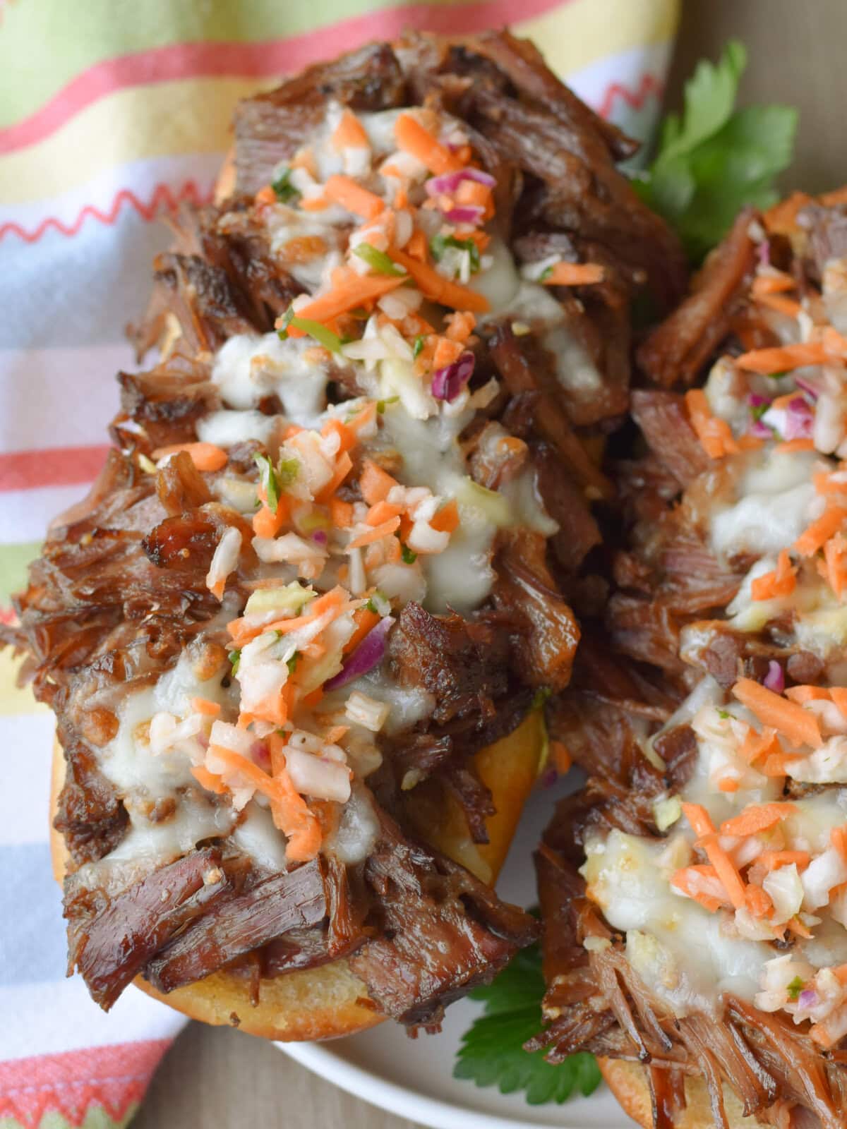 Garnished pulled beef sandwiches in the crock pot on a sub bun with cheese and a pickled vegetable garnish. 