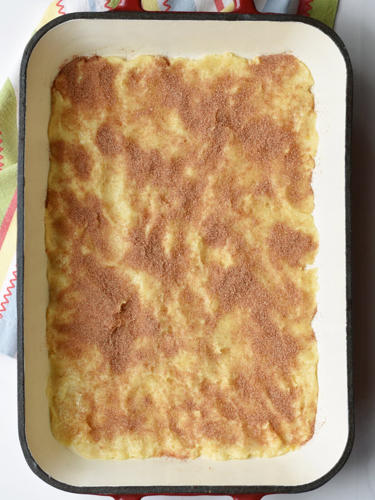 Dough spread along the bottom of a 9X13 pan with cinnamon and sugar on top. 