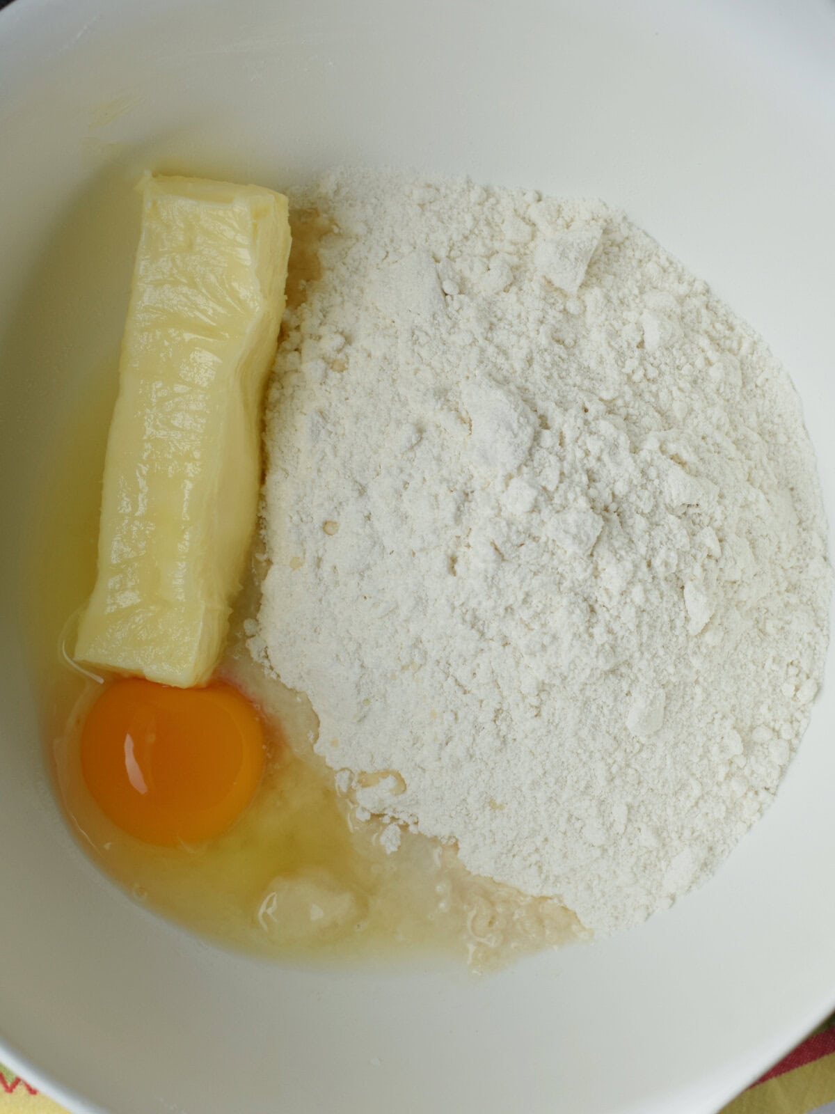 Cookie dough mix, egg and water in a white bowl. 