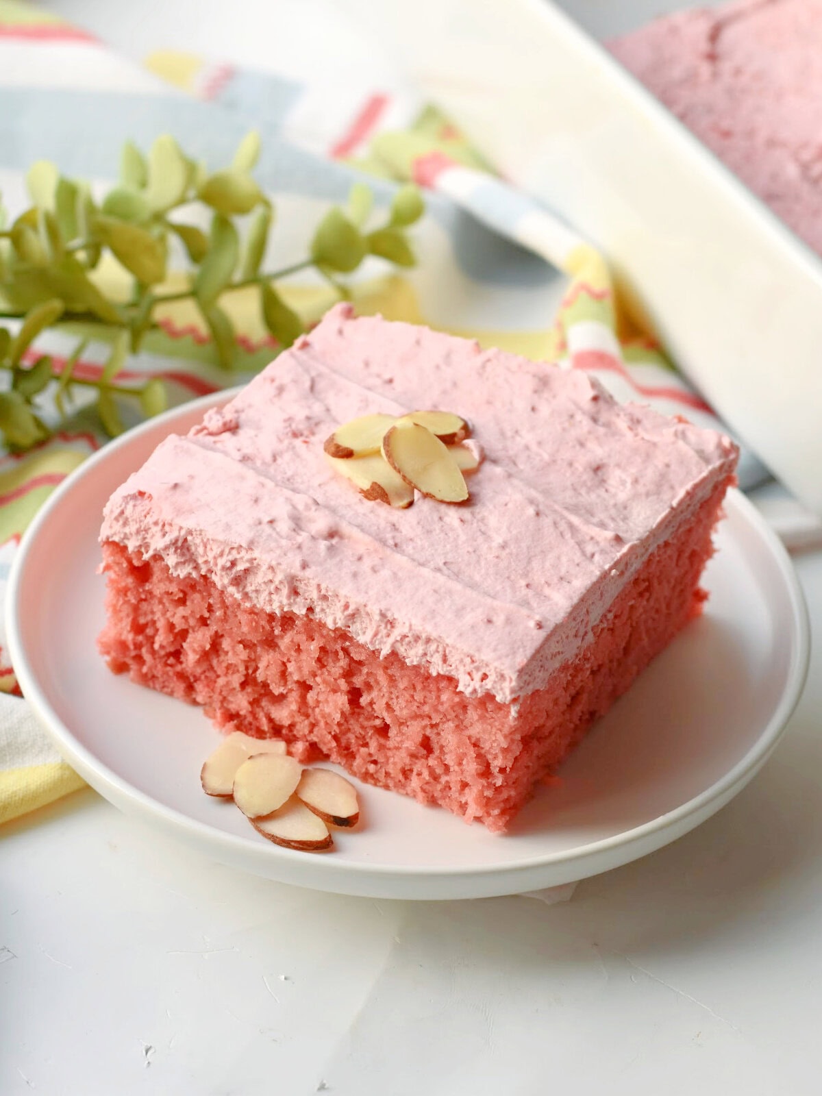 Cherry Almond Cake slice on a white serving plate with sliced almonds on top. 