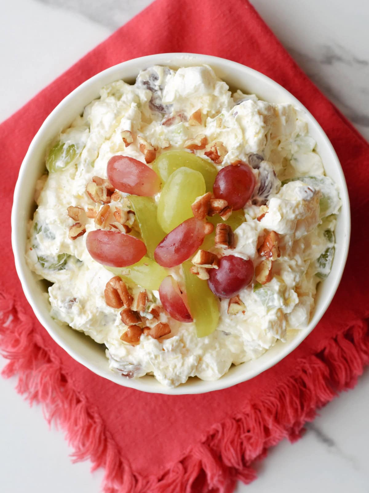 christmas-fruit-salad-topping Christmas fruit salad topped with grapes and pecans.