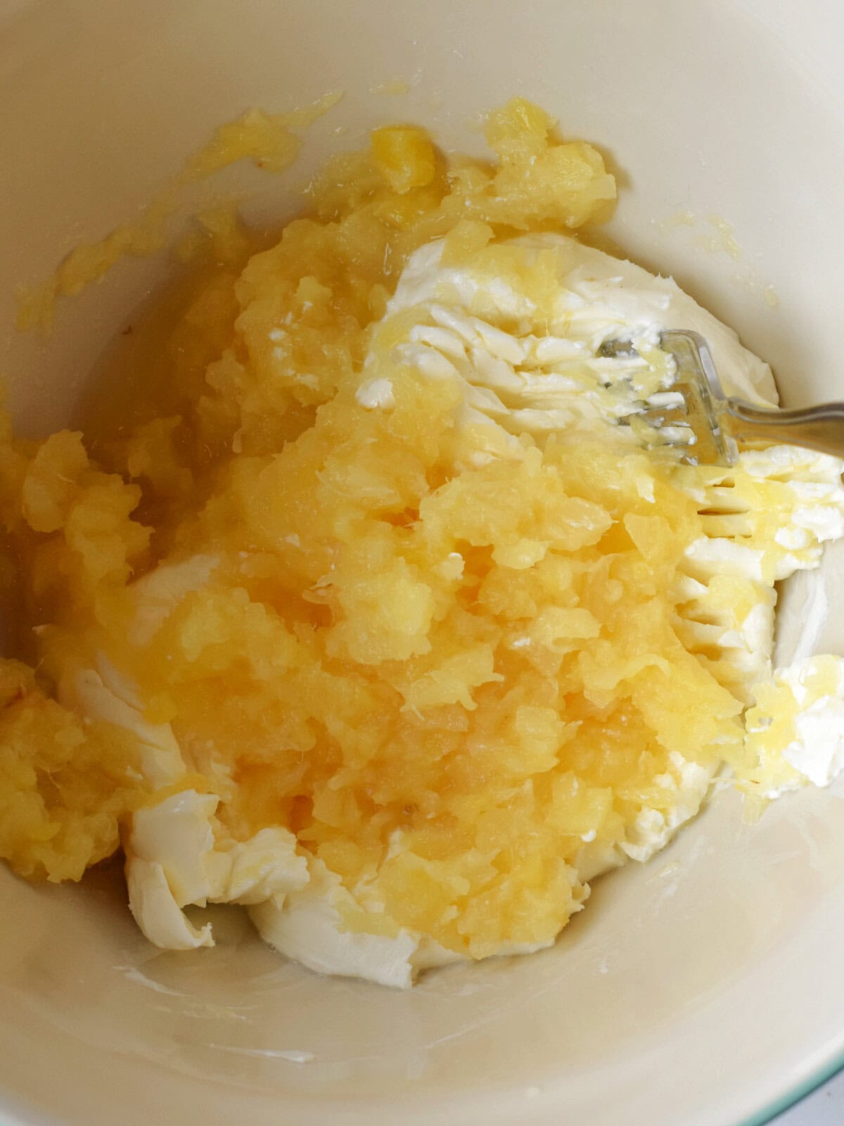 Christmas-Fruit-Salad-Pineapple Crushed pineapple and cream cheese being mixed together.