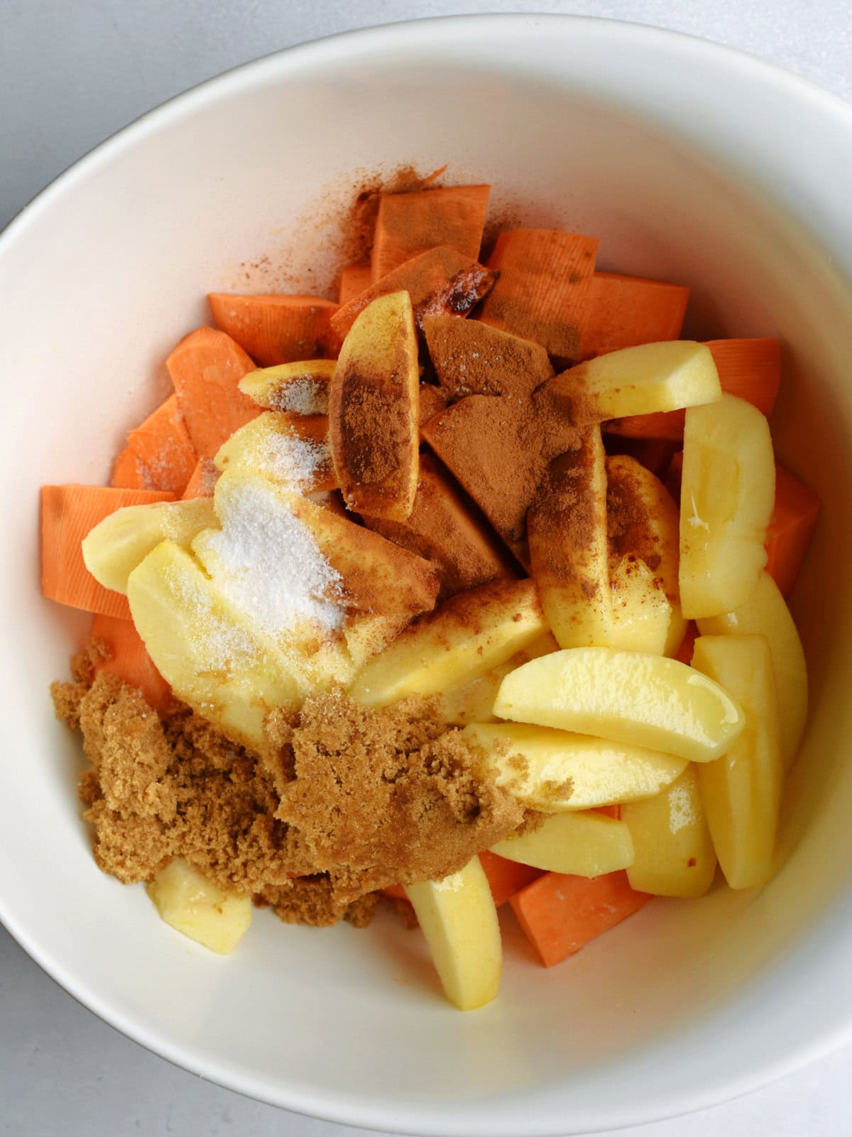 Raw ingredients with cinnamon and sugar in a mixing bowl. 