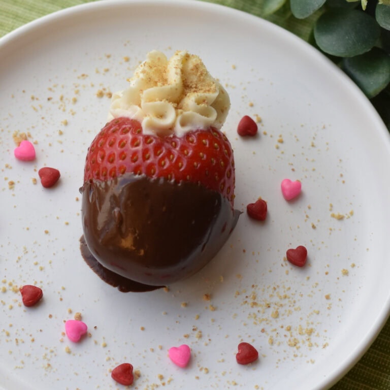 Deviled Cheesecake Strawberry with tiny heart spinkles on a white plate.