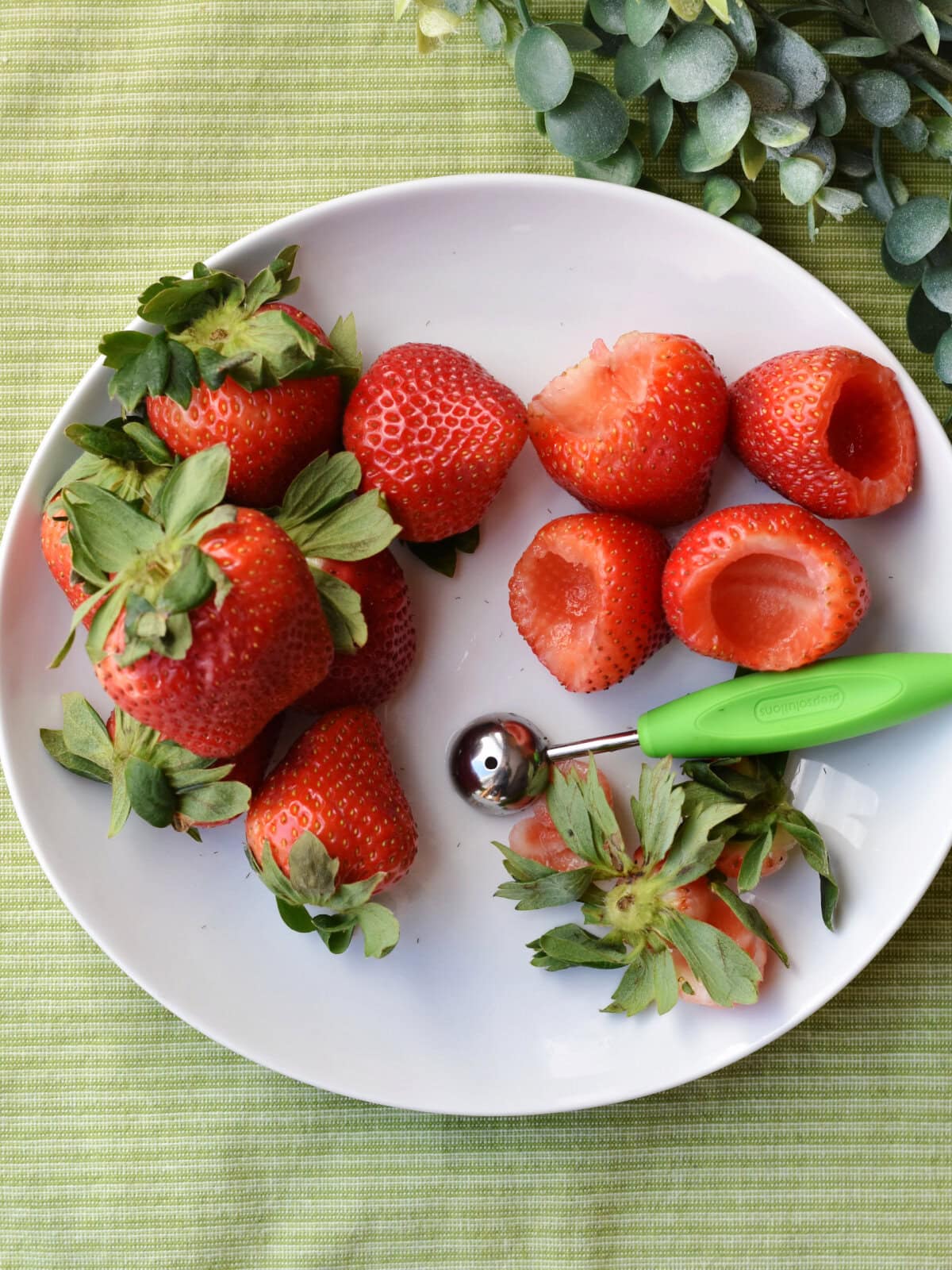 Scooping out the center of the strawberries with a melon baller. 