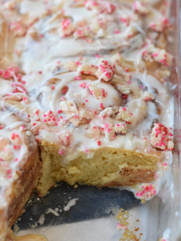 Sugar Cookie Cinnamon Rolls in a 9X13 glass pan with frosting and sugar cookie crumbles. 