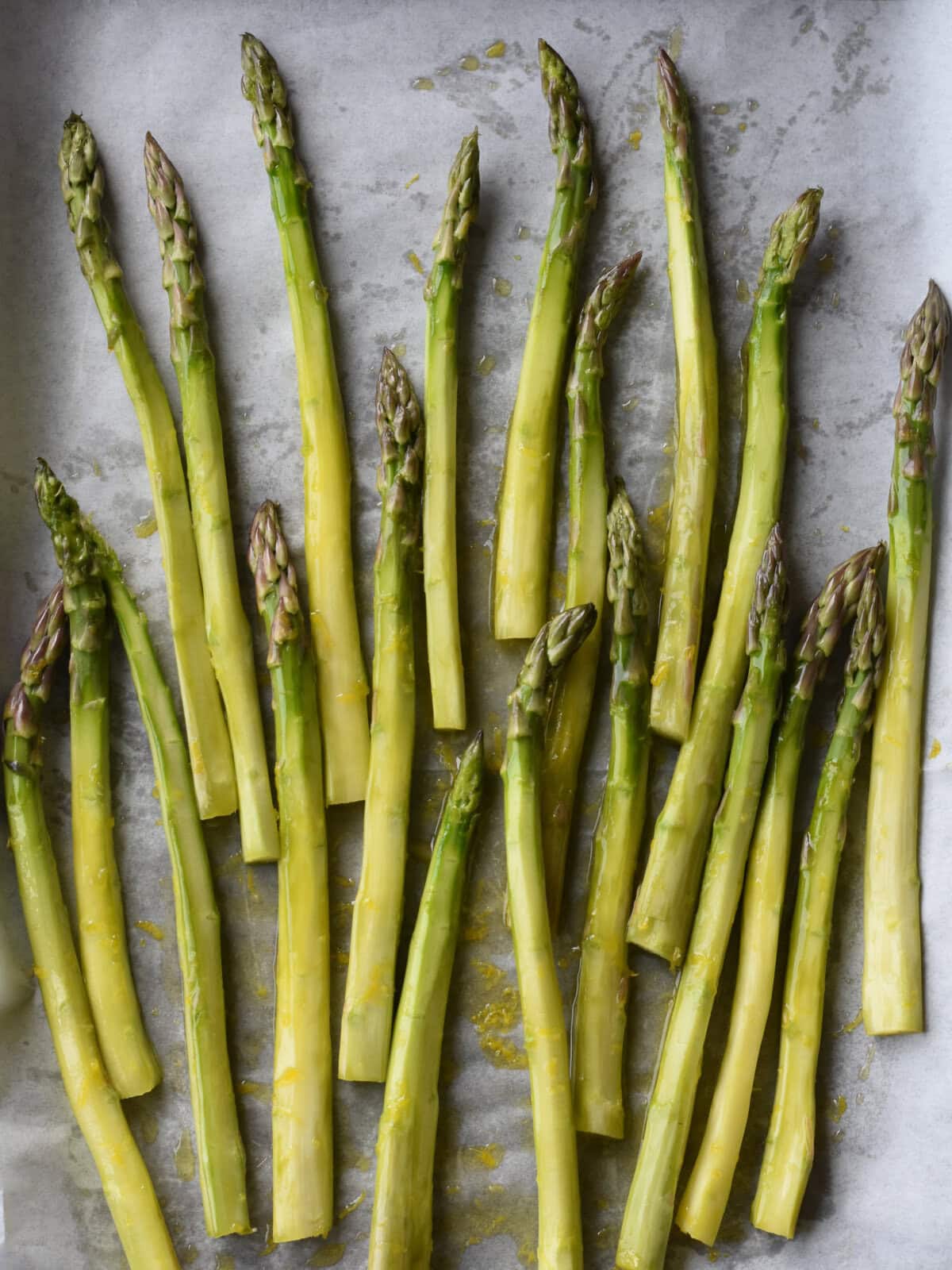 Tossed raw asparagus ready to roast. 