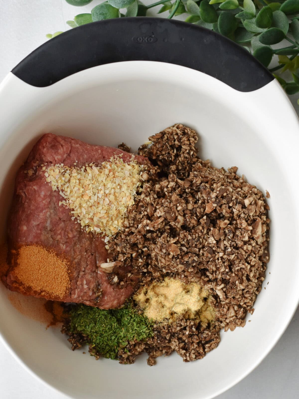 Ground beef, mushrooms and seasonings in a mixing bowl. 