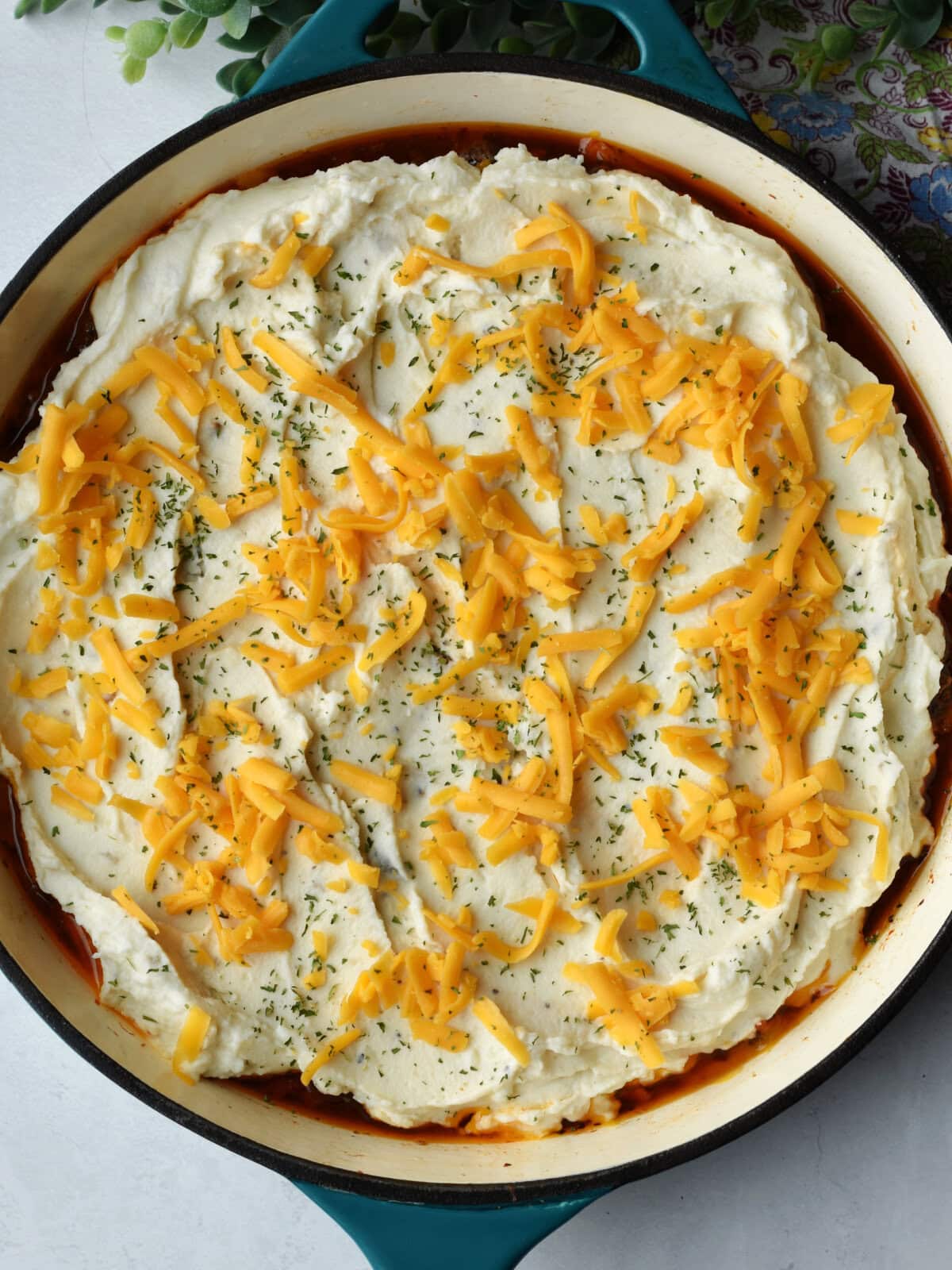 Shredded cheese, on top of a uncooked Shepards Pie. 