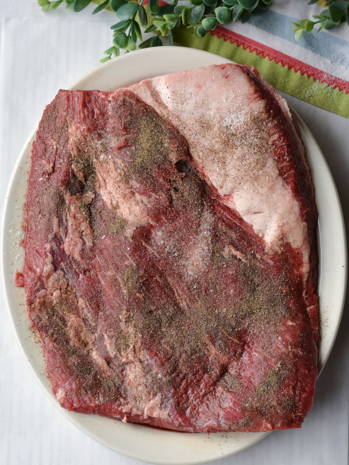 A trimmed uncooked beef brisket on a plate. 