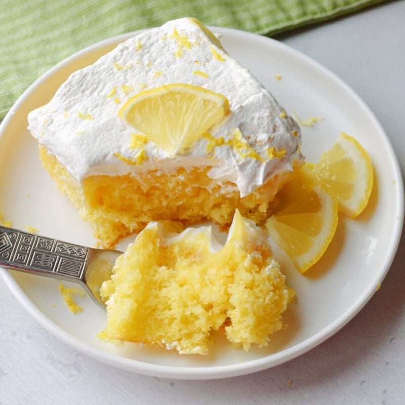 Lemon Poke Cake with fresh lemons as garnish.