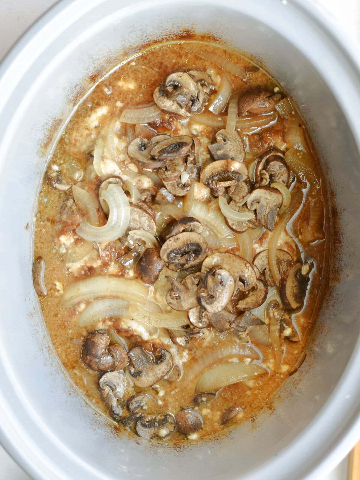 crockpot-round-steak-cooked Cooked tenderized beef with mushroom sauce in a slow cooker.