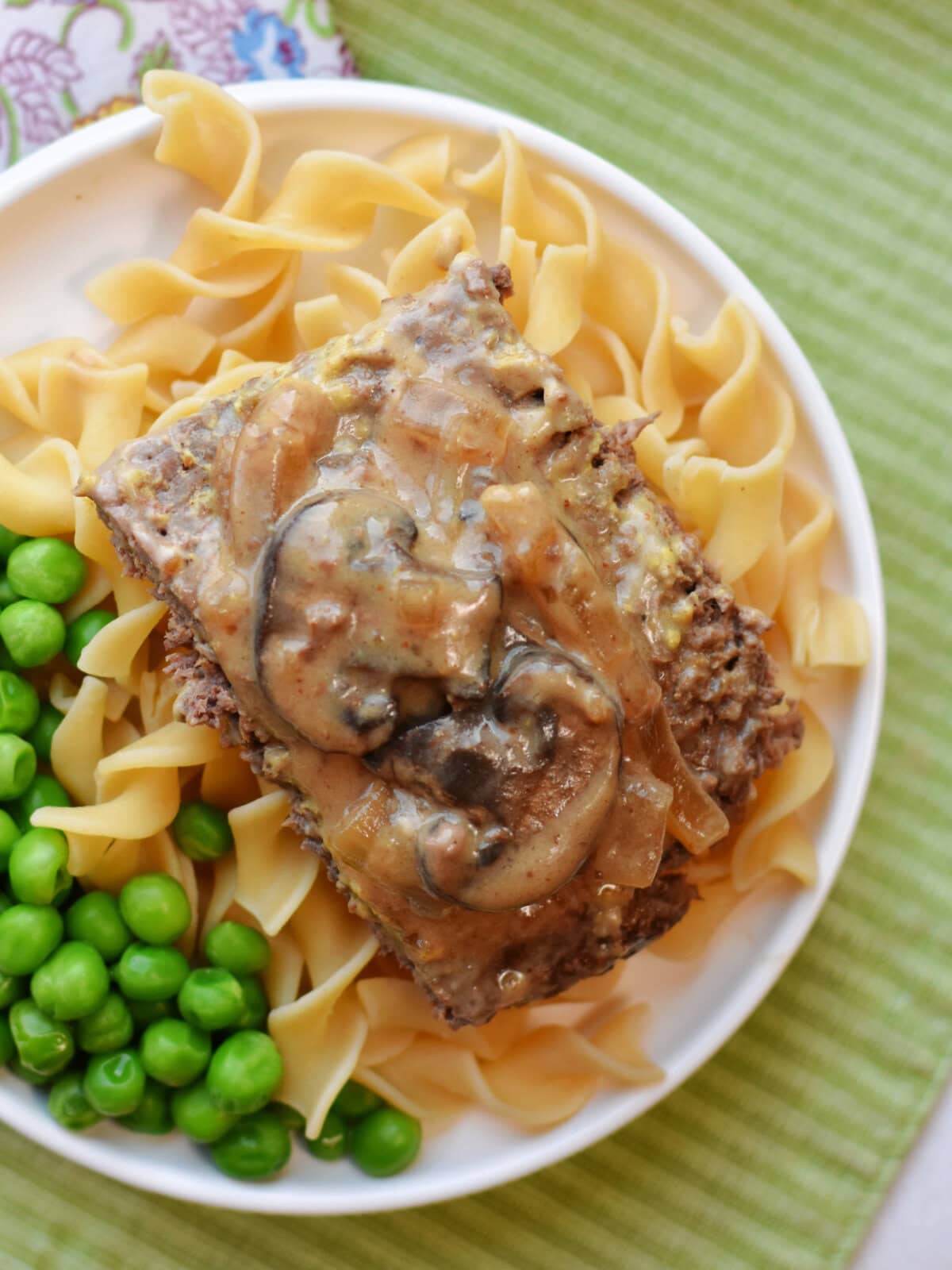 crockpot-round-steak-serving Crockpot round steak with mushroom gravy on a bed of noodles with peas.