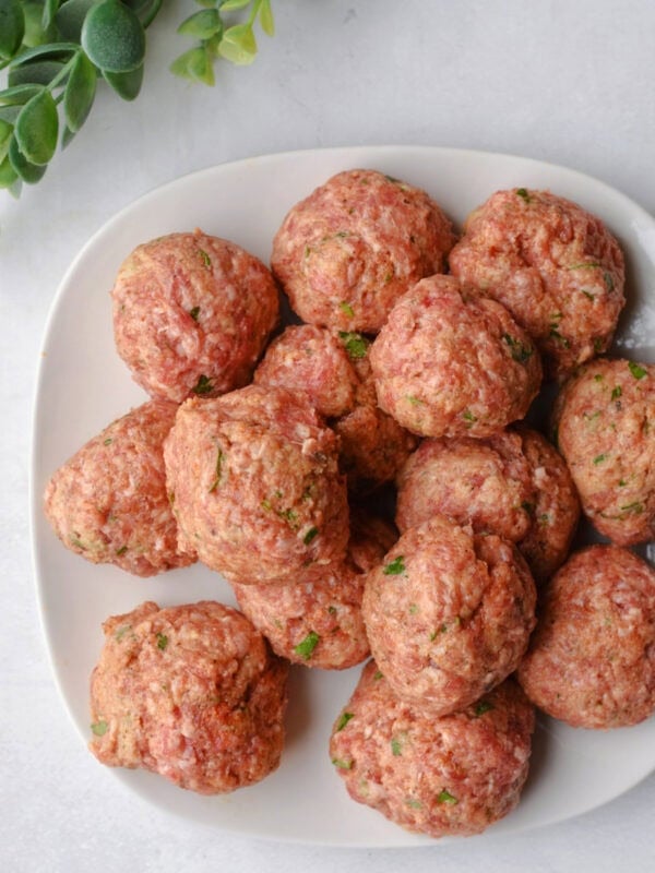 Raw ground pork balls on a white plate. 