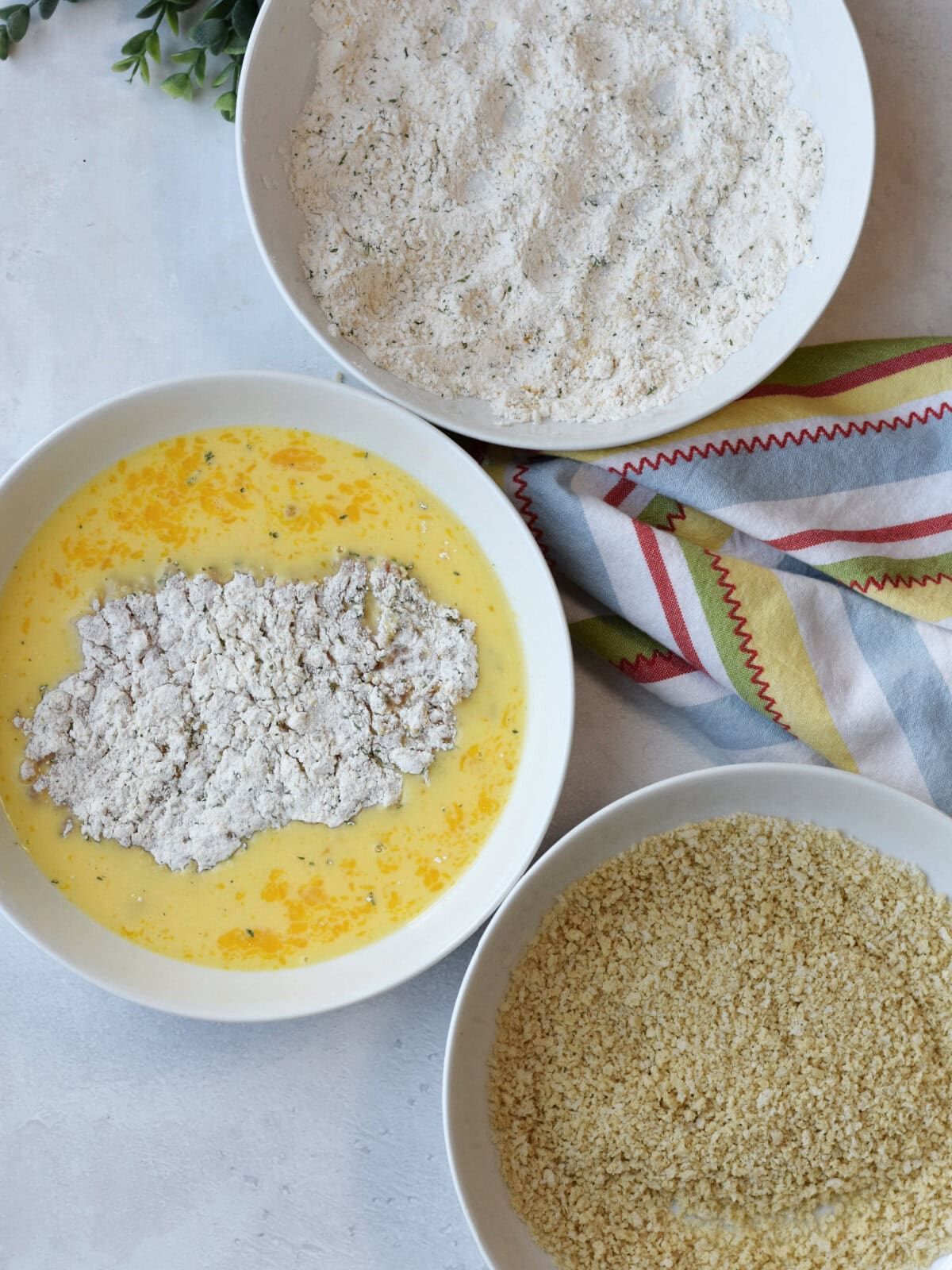 Breading meat in breading stations with panko bread crumbs and flour. 
