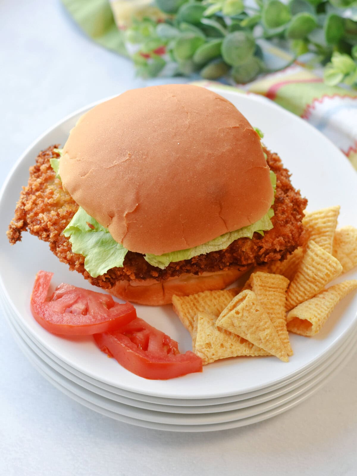 Fried pork cutlet sandwich with fresh sliced tomatoes and chips. 