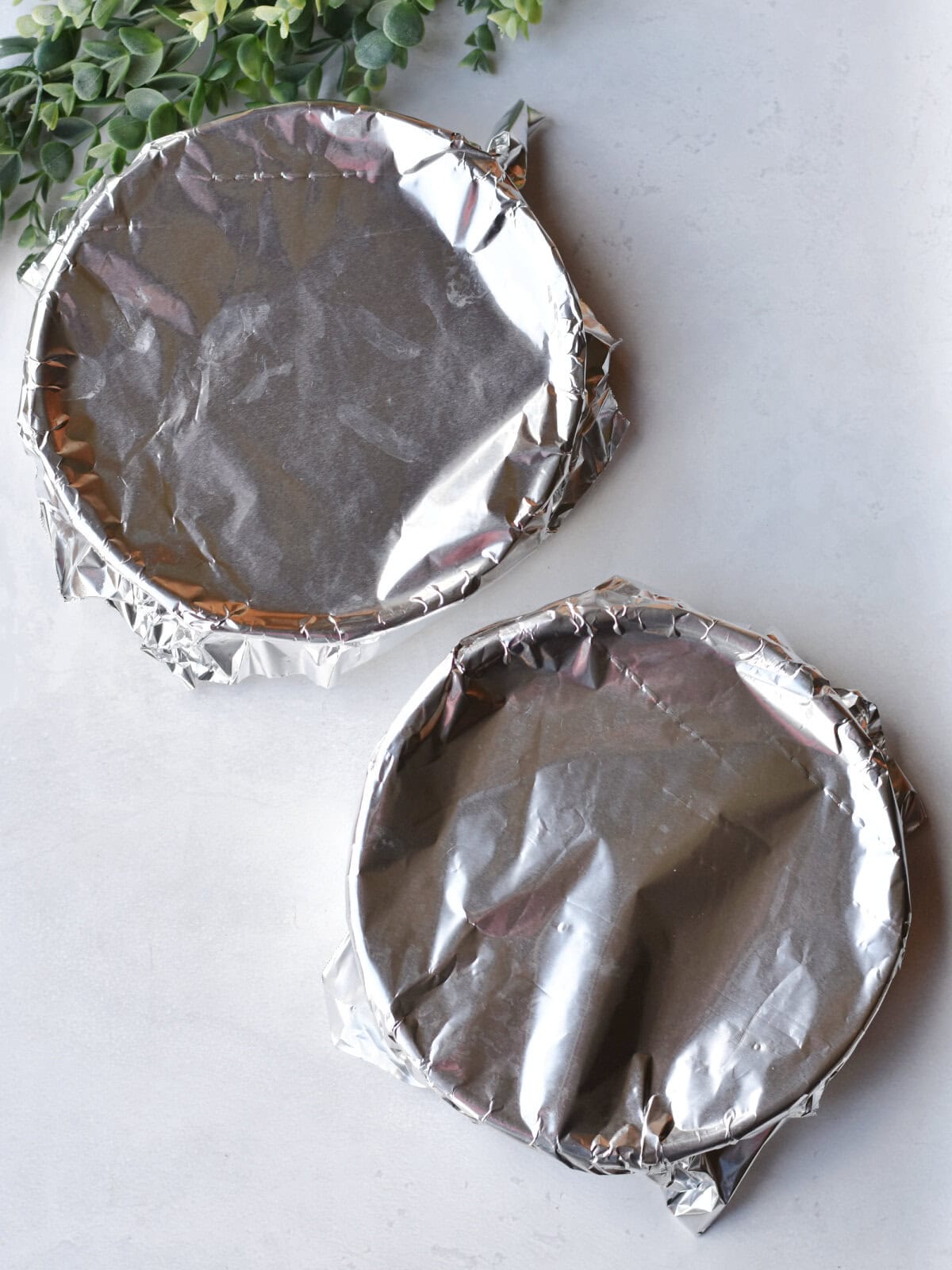 Baked cake cooling on a table with foil on top. 