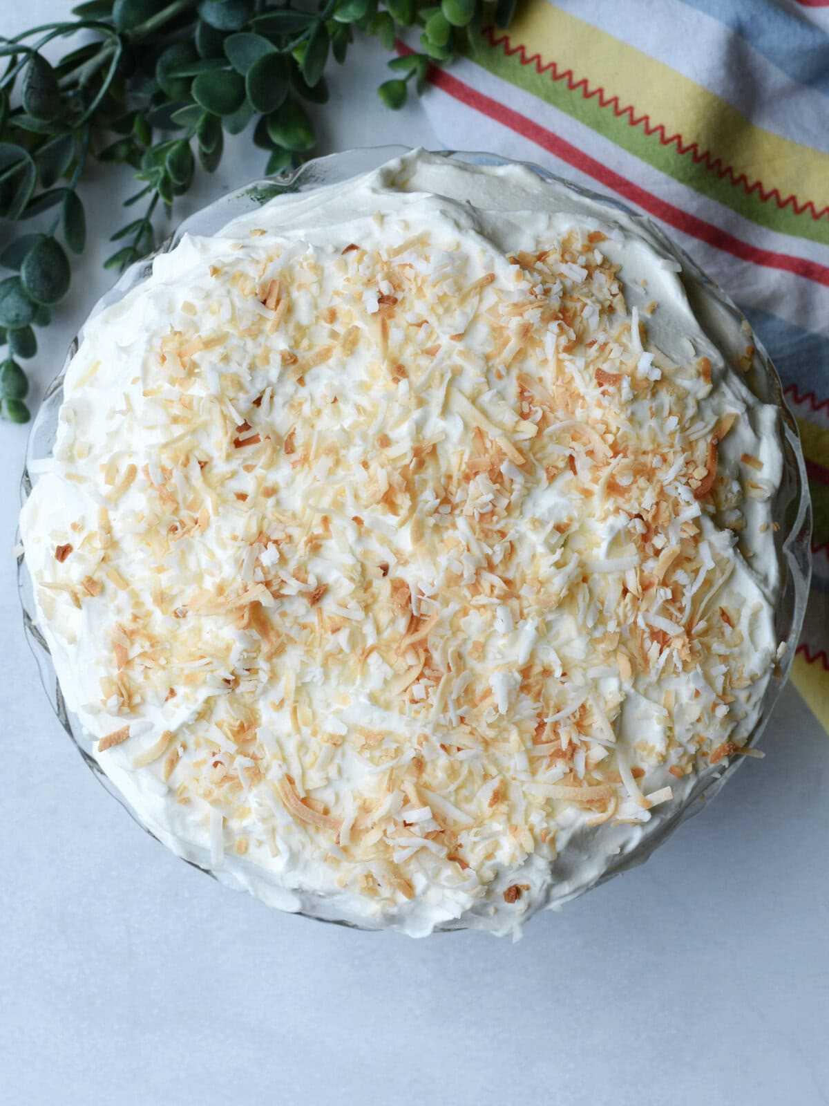 Cooled cake layer with frosting and shredded coconut. 