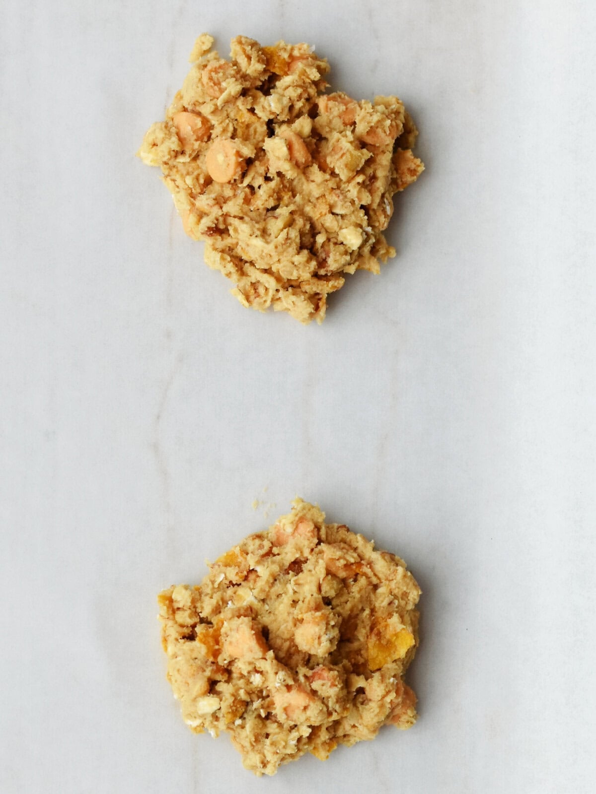 Heaping spoonfuls of uncooked cookies on a lined baking sheet. 