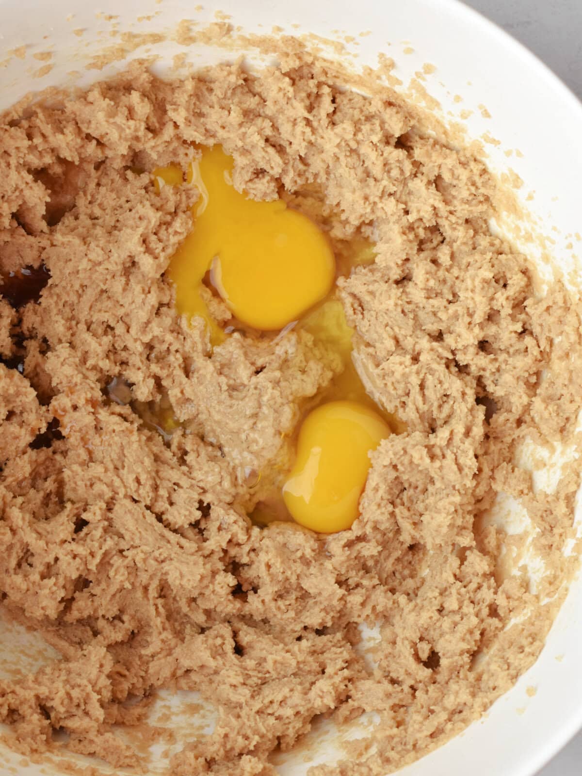 Batter in a mixing bowl with vanilla and eggs. 