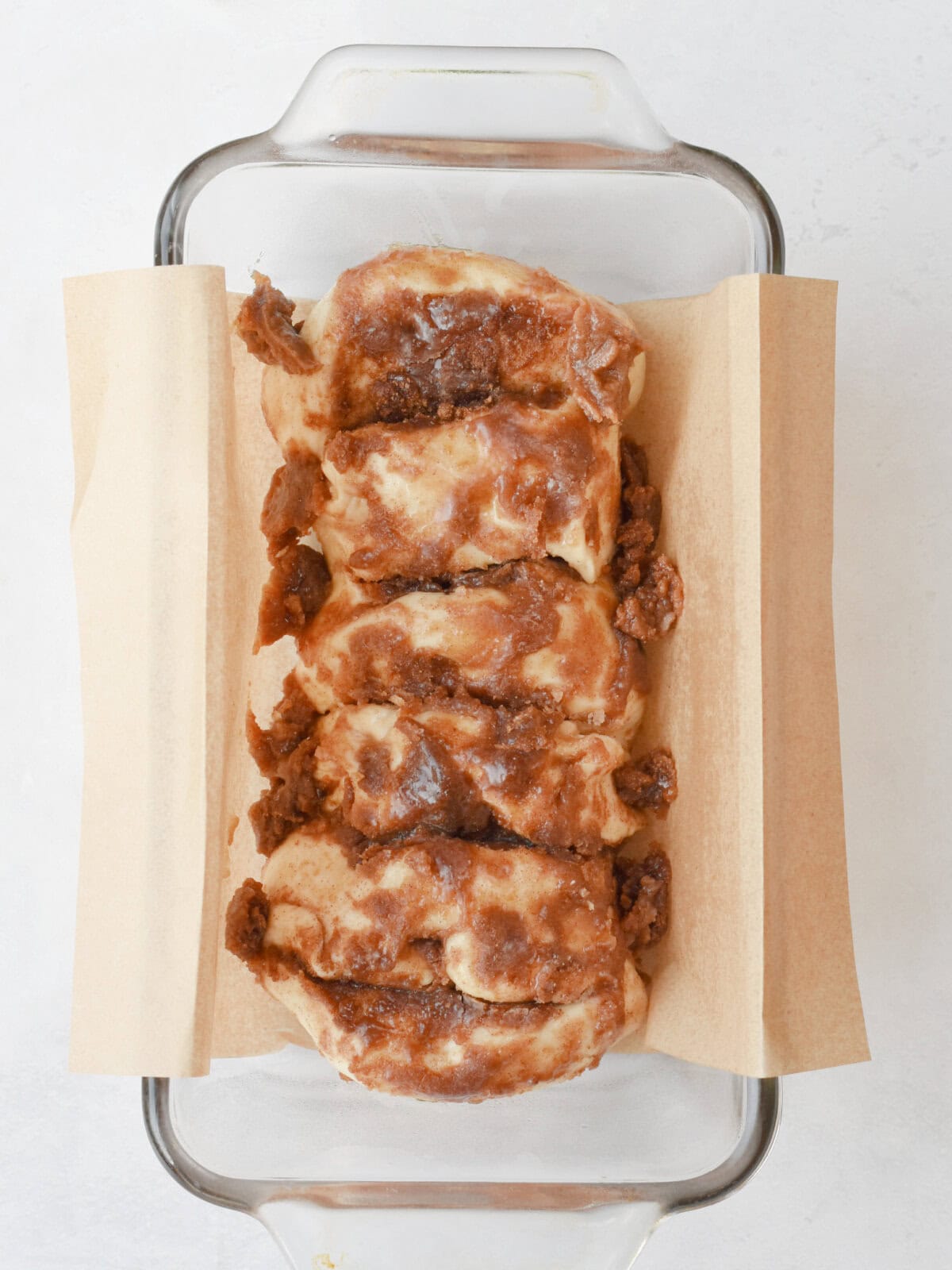 cinnamon-bread-uncooked Rhodes bread dough with cinnamon and sugar on parchment paper.