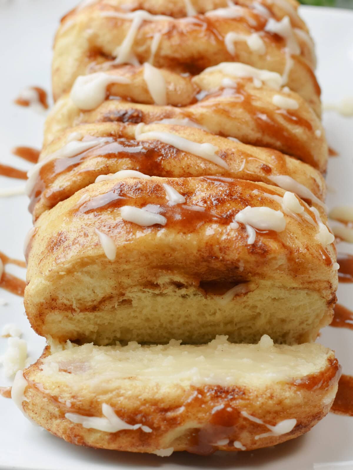 cinnamon-pull-apart-bread-slice Cinnamon Pull Apart Bread on a white serving plate with a slice cut out.