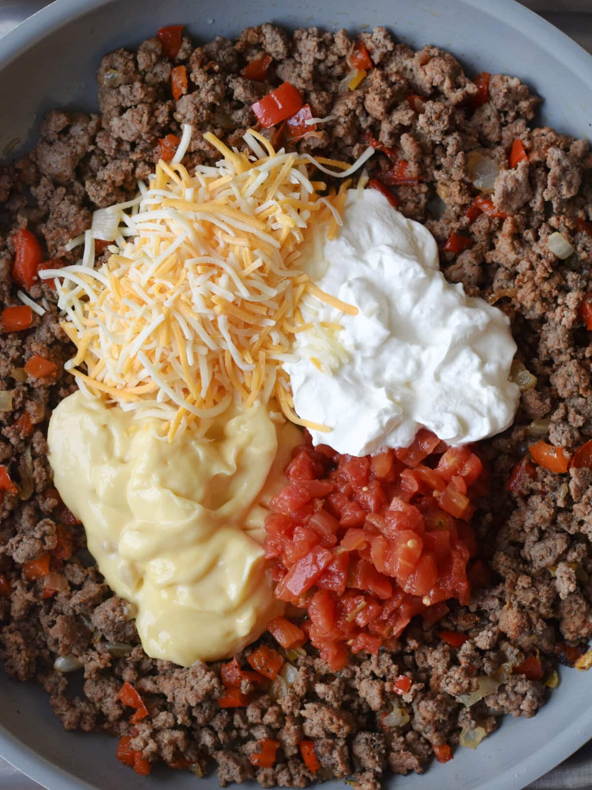 Creamy ingredients for the casserole added to the ground beef mixture in a skillet. 
